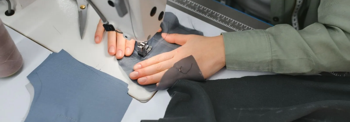 Hands working on a sewing machine, stitching high-tech fabric.