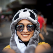 Woman in a playful animal hat and sunglasses smiling for a selfie.