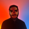 Person with an illuminated LED mask displaying a digital pattern, standing in front of a neon pink and blue background.